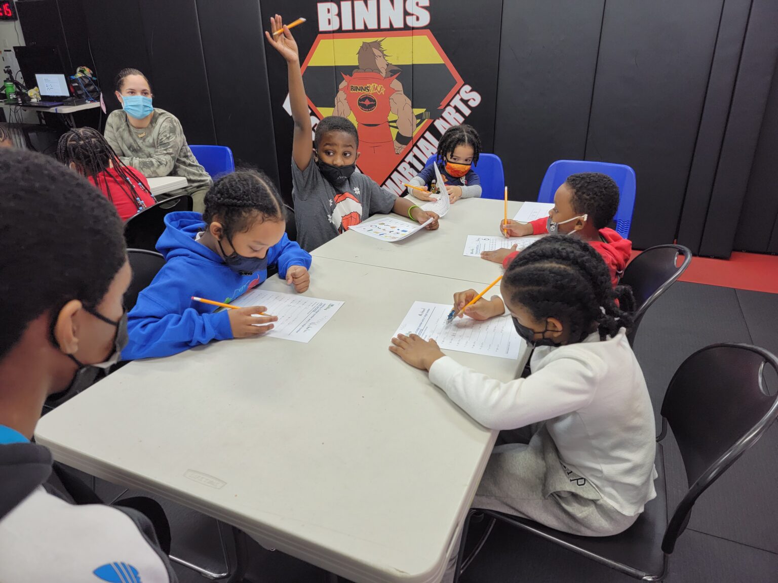 Kids focused on doing homework during the afterschool program at Binns Victory Martial Arts in Flatbush, promoting learning and discipline